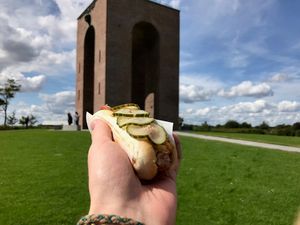 Ejer Bavnehøj, 16 August 2017 Hand holding hotdog in front of monument at
Ejer Bavnehøj